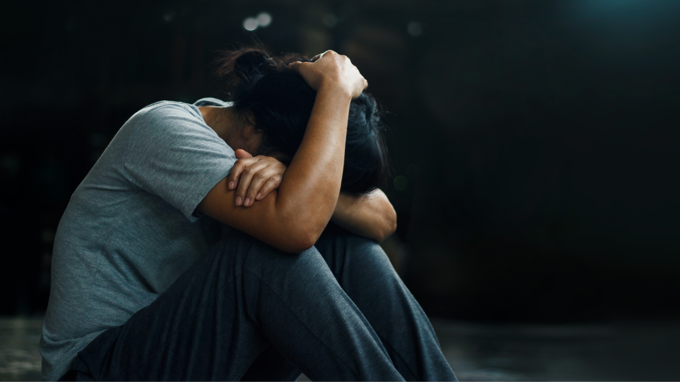 Personal sitting on floor, knees up holding her head in a mental crisis.