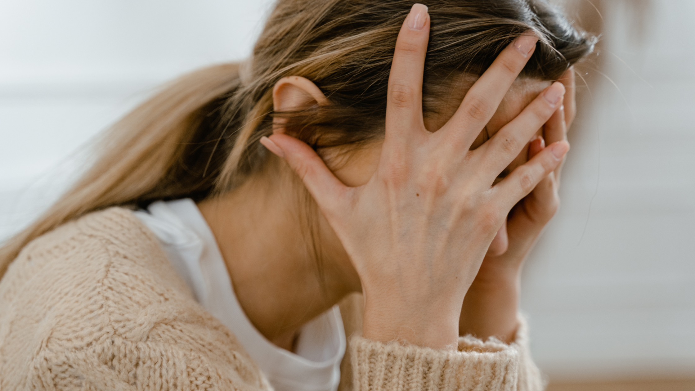woman holding her head in her hands looking disressed