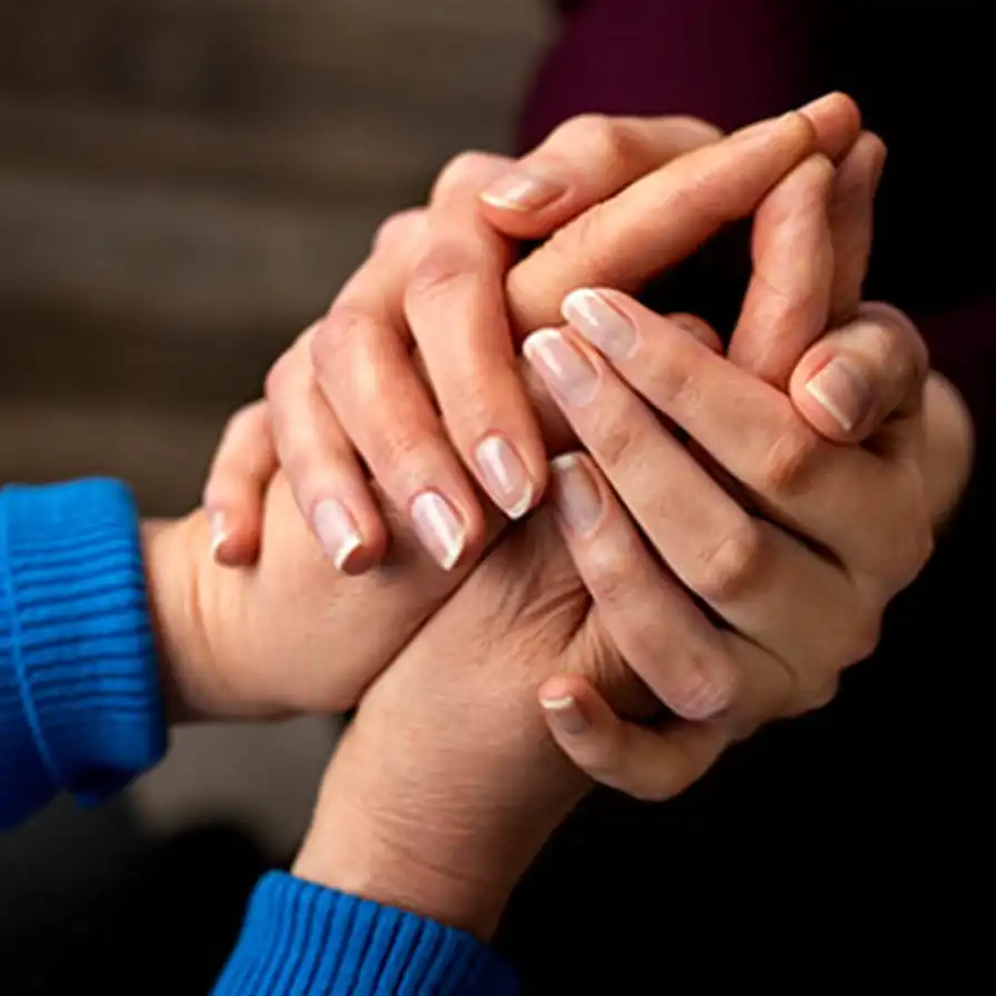 Close-up of two people holding hands in a supportive gesture